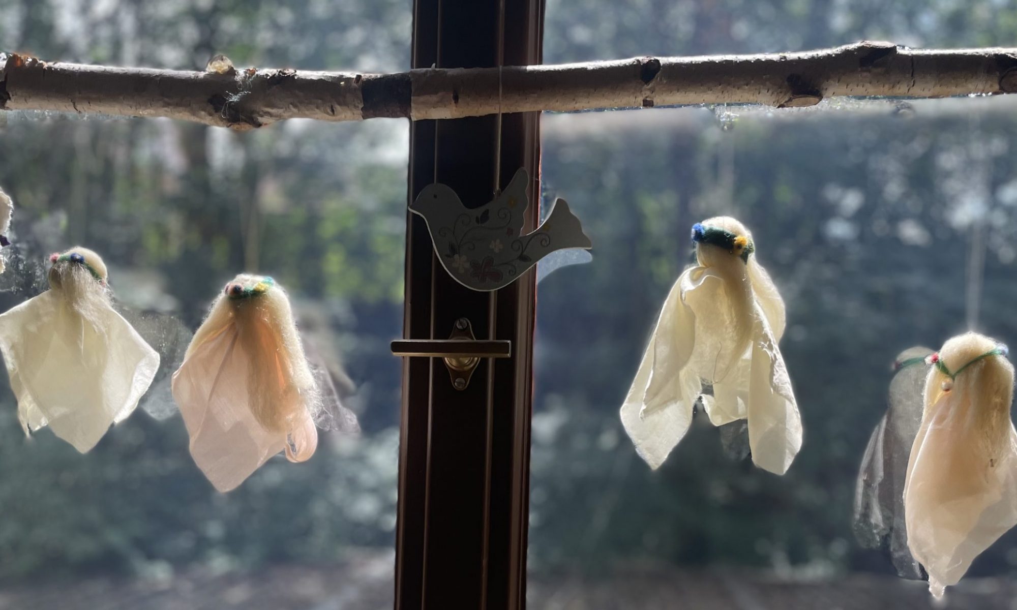 Feen aus Seidentüchern und Wolle hängen im Fenster